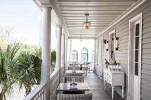 um alpendre com cadeiras e mesas de vime e um lustre em Hotel Bella Grace em Charleston