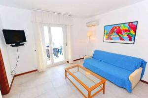 een woonkamer met een blauwe bank en een tv bij Apartments in Lignano 21657 in Lignano Sabbiadoro