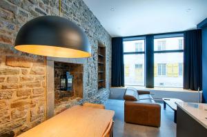 a living room with a stone fireplace and a table at Les Lofts Notre-Dame - Par Les Lofts Vieux-Québec in Quebec City