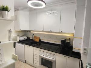 a kitchen with white cabinets and black counter tops at Apartament Pinada Beach in La Mata