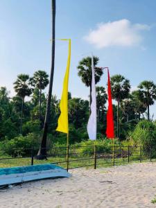 three flags on a fence on the beach at 108 Palms Beach Resort in Trincomalee