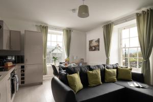 a living room with a black couch with yellow pillows at Glan Conwy House One and Two Bedroom Apartments in Llanrwst