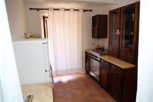 a kitchen with wooden cabinets and a white curtain at Casa Serena Country house in Tuscany. in Sorano +4 photos