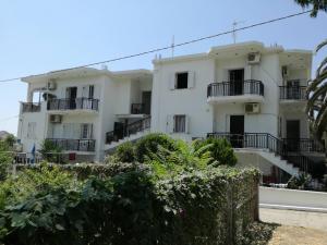 a white apartment building with balconies and bushes at Αλέξανδρος 6 in Mirina