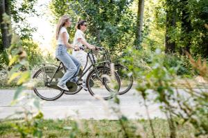 two women riding a bike down a path at les Cabanes d'Ostende in Ostend