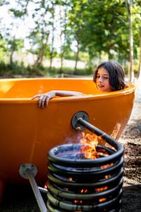 une femme assise dans un bain orange à côté d'un feu dans l'établissement les Cabanes d'Ostende, à Ostende