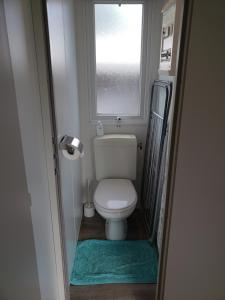 baño pequeño con aseo y ventana en MOBIL-HOME CONFORTABLE ET BIEN EQUIPE AVEC PISCINES ET LA PLAGE A PIED, en Fouesnant