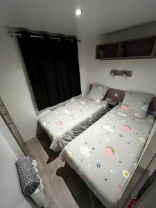 2 camas individuales en una habitación con ventana en MOBIL-HOME CONFORTABLE ET BIEN EQUIPE AVEC PISCINES ET LA PLAGE A PIED, en Fouesnant