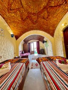 a bedroom with two beds in a room with a ceiling at Kendaka Nubian House in Aswan