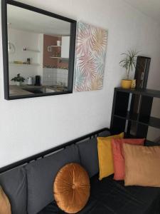 - un canapé noir avec des oreillers colorés assis sous un miroir dans l'établissement Cozy'Nest, à Brest