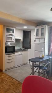 cocina con electrodomésticos blancos y mesa con silla roja en Apartamento Bubal, en Panticosa