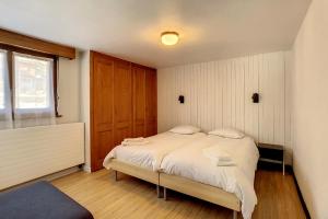 a bedroom with a bed with white sheets at Ambassador 001 in Verbier