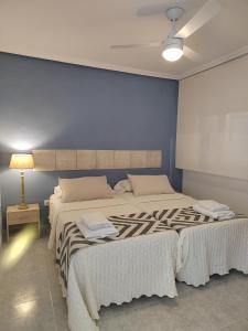 Apartamento Santa Pola في سانتا بولا: غرفة نوم بسريرين وجدار ازرق