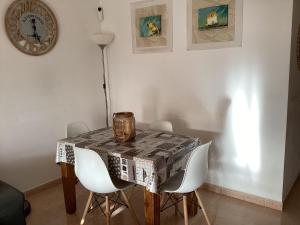 mesa de comedor con sillas blancas y reloj en Fuerteventura House Wifi -, en Corralejo