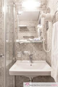 La salle de bains blanche est pourvue d'un lavabo et d'une douche. dans l'établissement Marins Park Hotel Nizhny Novgorod, à Nijni Novgorod