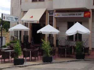 an outdoor cafe with tables and chairs and umbrellas at Hotel Puente Romano in Alcántara