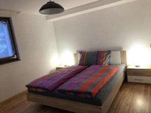 a bedroom with a bed with a colorful blanket on it at Wohnung Chalet Veilchen in Herbriggen