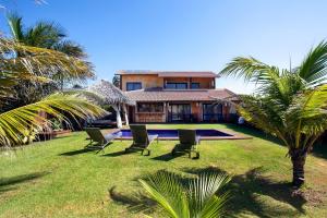 een huis met een tuin met stoelen en een zwembad bij Zorah Beach Hotel in Trairi