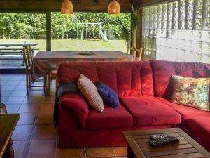 un sofá rojo en una sala de estar con mesa en Casa Rural Yolanda para 5 personas, en Arangas