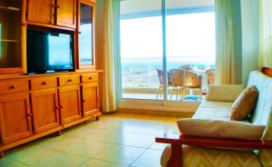a living room with a tv and a large window at desolyplaya Colomeras 3T in Oropesa del Mar