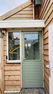 Una puerta a una casa con una flecha amarilla. en The Birdhouse, Tiny home close to the beach en Noordwijk aan Zee