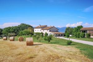 a field with hay bales in front of a house at Relais Casale Valigi in Narni