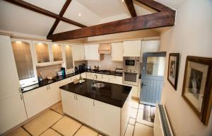 a large kitchen with white cabinets and a wooden ceiling at Beckside Cottage, Netherby, near Carlisle in Longtown