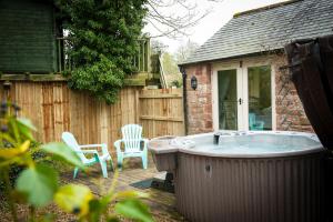 a hot tub in a yard with two chairs at Beckside Cottage, Netherby, near Carlisle in Longtown