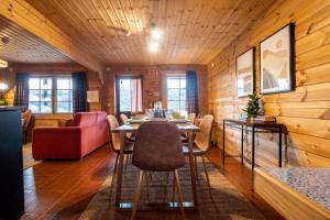 a dining room with a table and a red couch at Chalé de Montanha com sons de rio in Cortes do Meio