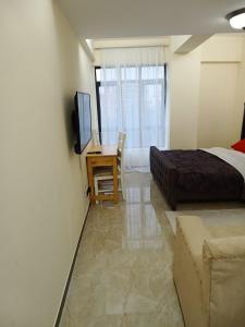 um quarto com uma cama e uma secretária com uma televisão em Lux Suites Dennis Pritt studio Apartments Kilimani em Nairobi