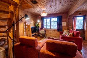 a living room with a couch and chairs in a cabin at Chalé de Montanha com sons de rio in Cortes do Meio +34 photos