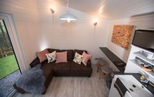 a living room with a brown couch and a tv at Reflections, Netherby, near Carlisle in Longtown