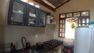 cocina con fogones, nevera y ventana en Belaninha en Guaramiranga