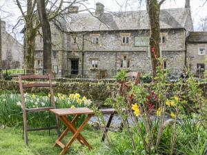 a garden with two chairs and flowers in front of a stone building at The Threshing Floor at Tennant Barn in Skipton