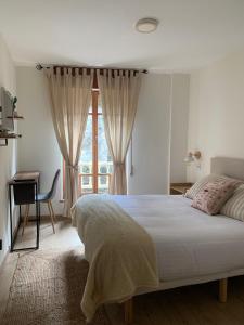 1 dormitorio con cama, escritorio y ventana en Pensión Cantabrico, en Navia