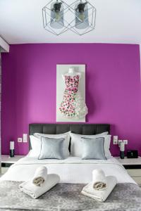 a bedroom with purple walls and a bed with two towels at Casa di Gio in Kalabaka