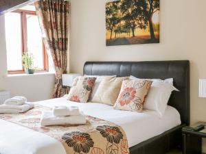 a bed with a black leather headboard and pillows at The Hayloft at Tennant Barn in Skipton