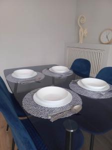 un tavolo nero con piatti bianchi e sedie blu di Apartament w centrum Raciborza a Racibórz