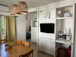a dining room with a table with a microwave and a tv at Dunas Delfin in Monte Hermoso