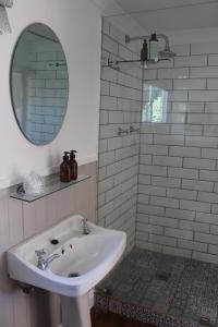 een badkamer met een wastafel, een spiegel en een douche bij Cheverells Farm in Grabouw