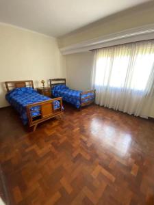 sala de estar con 2 camas y suelo de madera en Casa JUCALI en Tandil