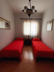 2 camas rojas en una habitación con ventana en Casa JUCALI en Tandil