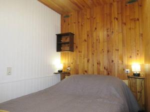 Au Coeur du village de Prémanon في بريمانون: غرفة نوم بسرير في جدار خشبي