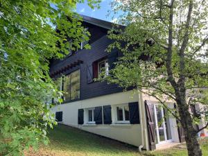 une maison noire et blanche avec un arbre dans l'établissement Au Coeur du village de Prémanon, à Prémanon