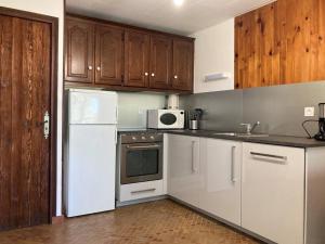 a kitchen with white appliances and wooden cabinets at Au Coeur du village de Prémanon in Prémanon