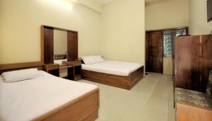 a bedroom with two beds and a mirror at Hotel Sea Queen in Cox's Bazar