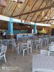 a restaurant with white tables and chairs and a bar at Best Luxury Samaria in Santa Marta
