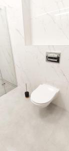 La salle de bains blanche est pourvue de toilettes et d'un miroir. dans l'établissement Apartament na Letniej 53m2 z Widokiem na Góry Kłodzko - Przyjaciół Ziemi Kłodzkiej, à Kłodzko