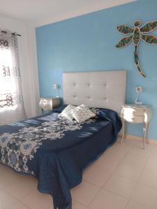 a bedroom with a bed and a blue wall at Casa Libélula in Costa Del Silencio