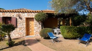 two blue chairs and a table in front of a house at Welcomely - Sa Perda in Tortolì